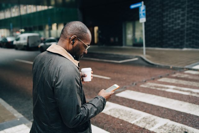 businessman walking on street looking at phone