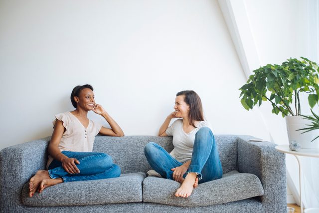 two friends sitting on couch at home talking