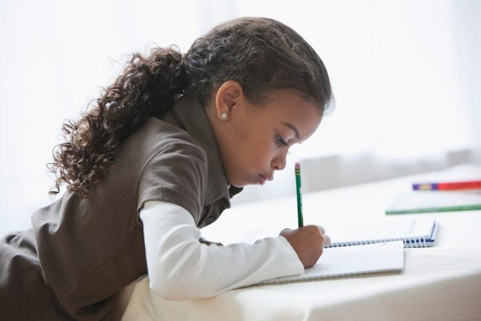 young girl writing doing homework