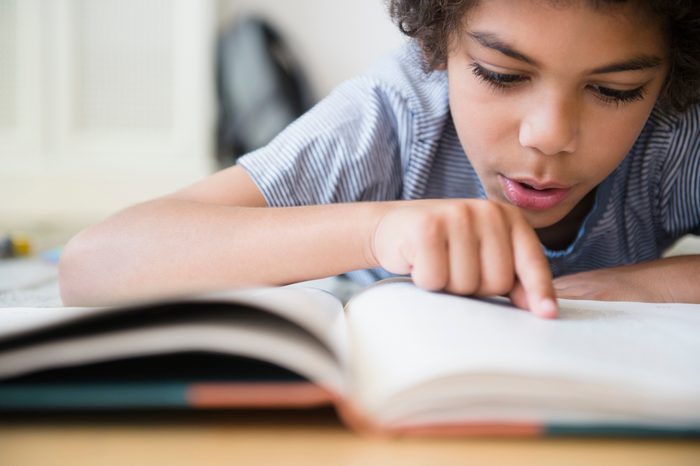 young boy reading a book close up