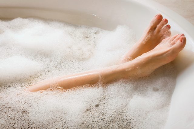 close up of woman's legs in soapy bathtub