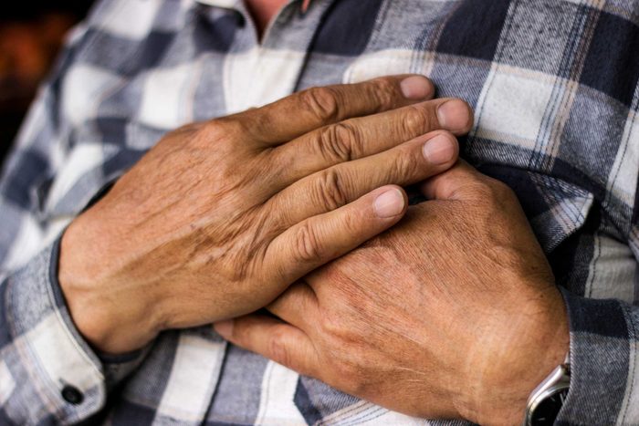 older man holding his hands over his chest