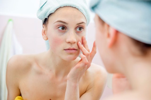 woman just out of the shower checking her face in the mirror