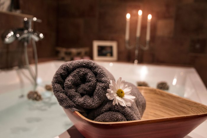 rolled towels next to candlelit bathtub