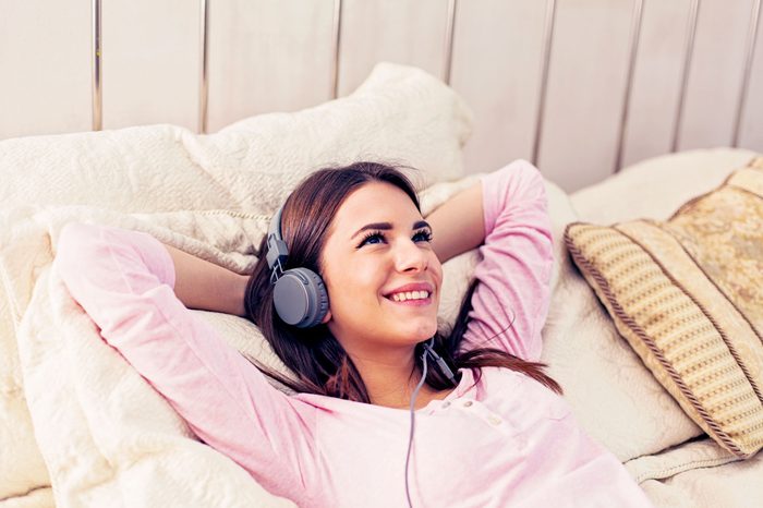 woman listening to headphones in bed