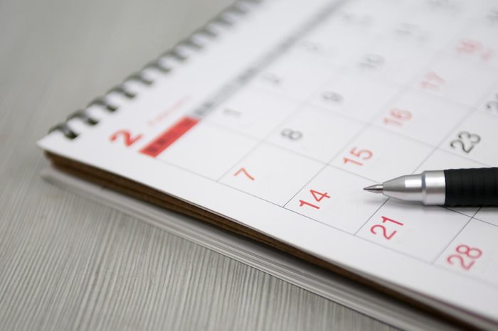 Calendar resting on a gray surface with a pen on it.
