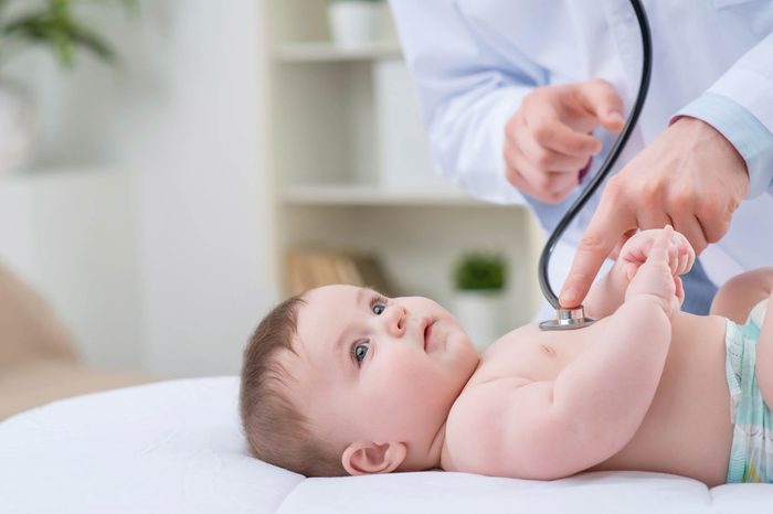 doctor checking infant on bed with stethoscope