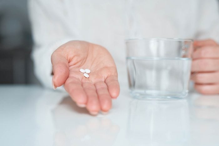 hand holding pills and a waterglass