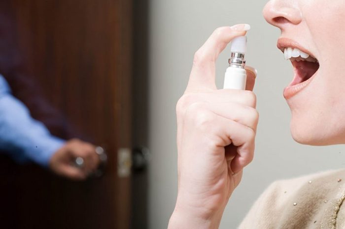 Woman spraying breathe freshener in mouth