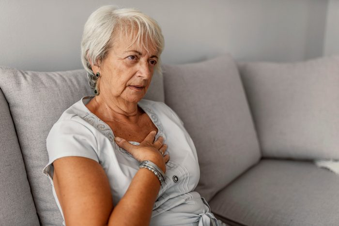 woman with shortness of breath while sitting on couch at home