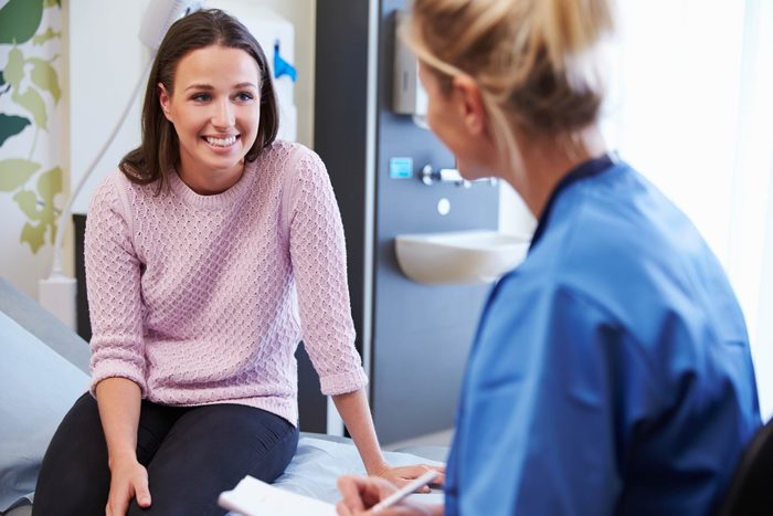 Smiling woman talking to doctor in office.
