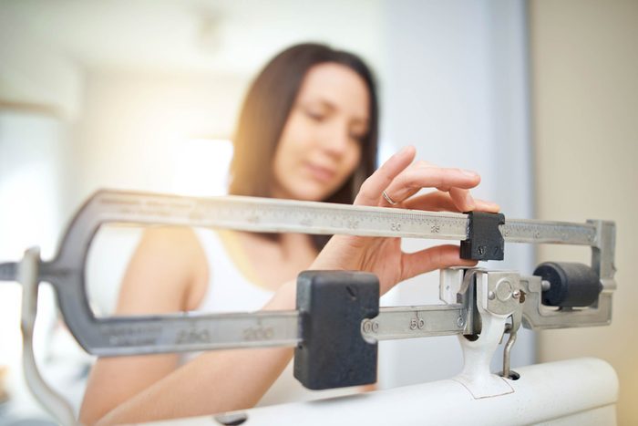 woman weighing self on scale