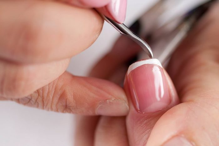 shaping nails with a manicurist's tool