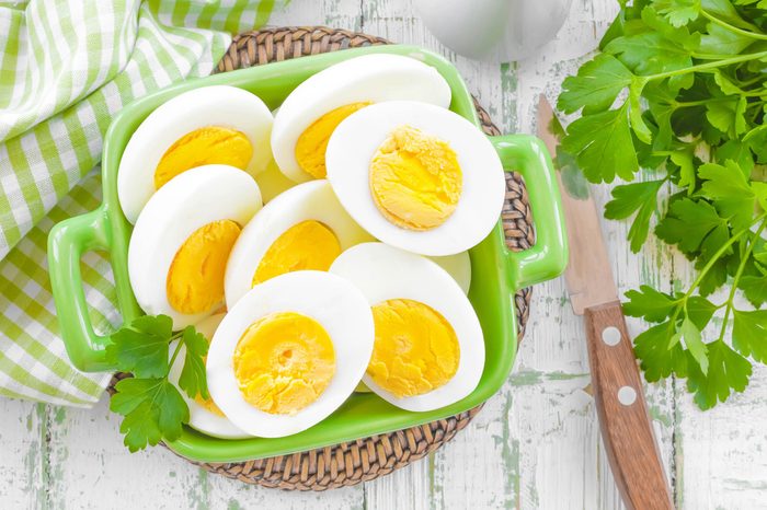 halves of boiled, peeled eggs in a green dish