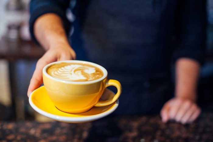 barista serving coffee in yellow cup
