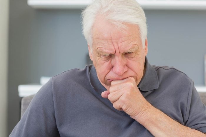 elderly man coughing into his hand
