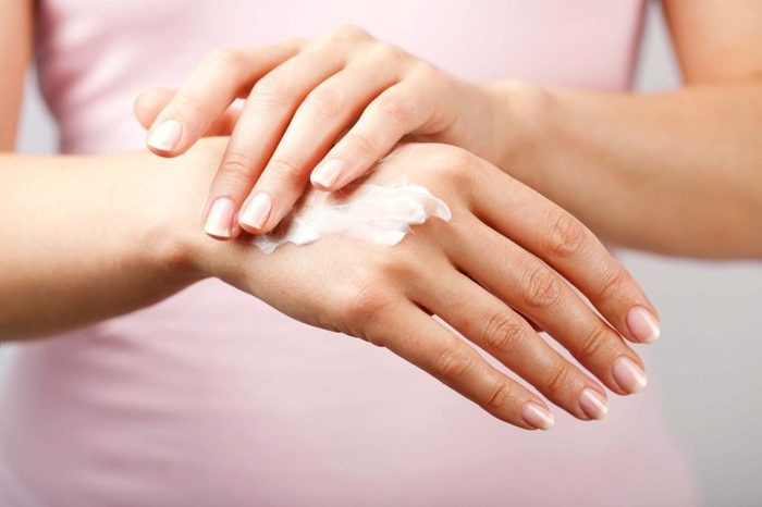 hands rubbing cream on skin
