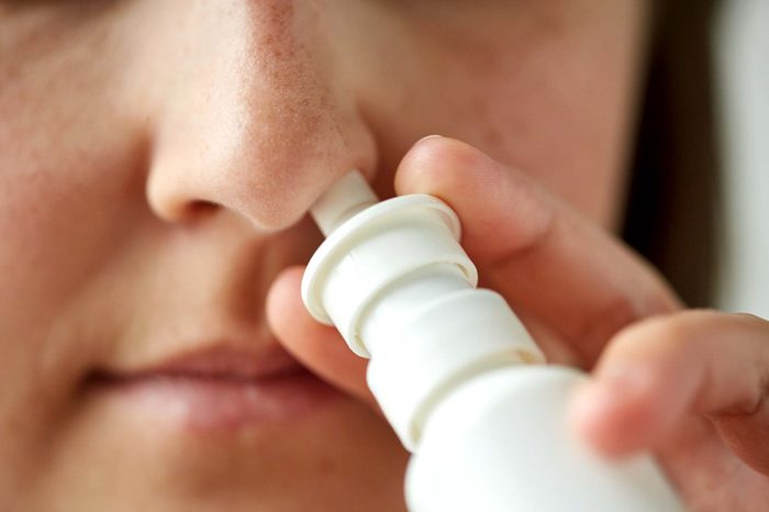 close up of a woman using a nasal inhaler