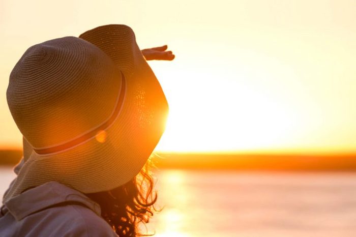 woman wearing a hat gazing at a sunset