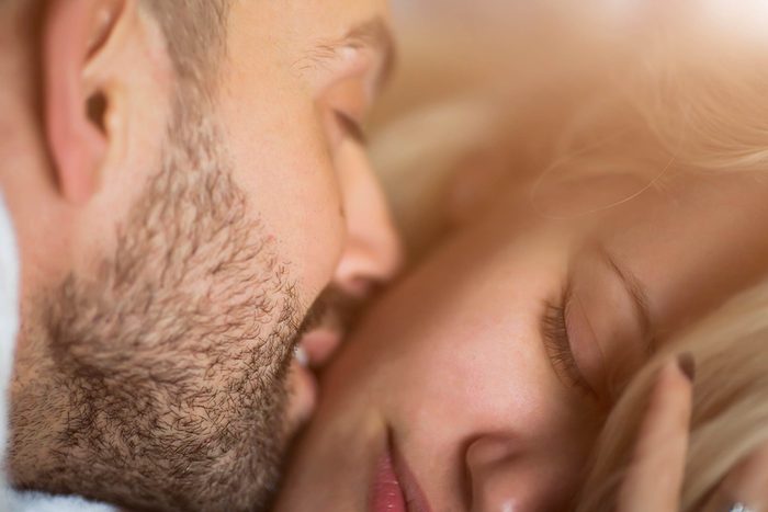 man kissing woman's cheek, both eyes closed