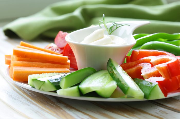 sliced vegetables on a plate surrounding cup of dip