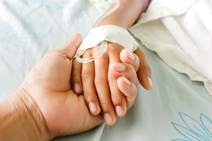 adult holding a child's hand with IV