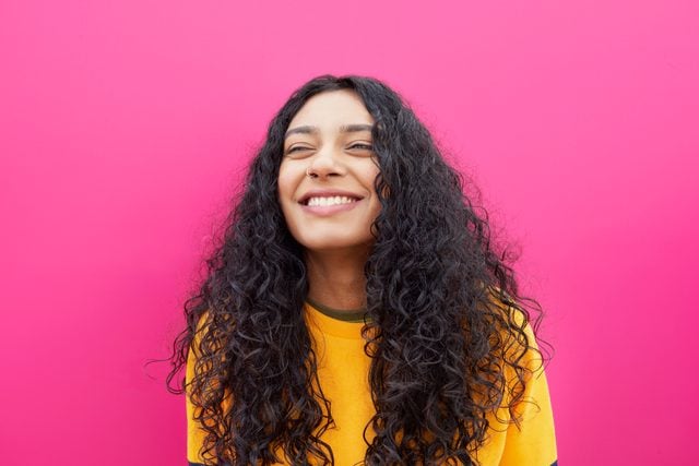 young woman smiling on pink background