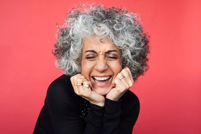 mature woman laughing on red background