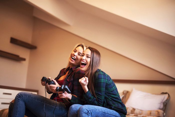 Two women playing video games and laughing.