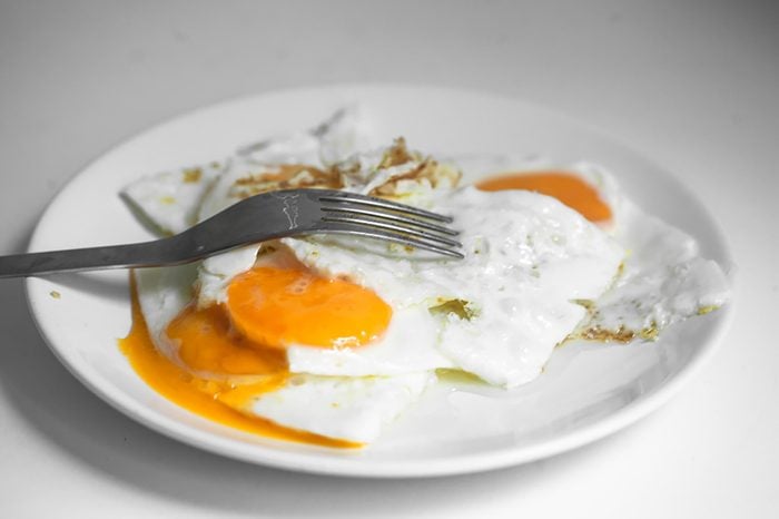 eggs over easy on a white plate with a fork