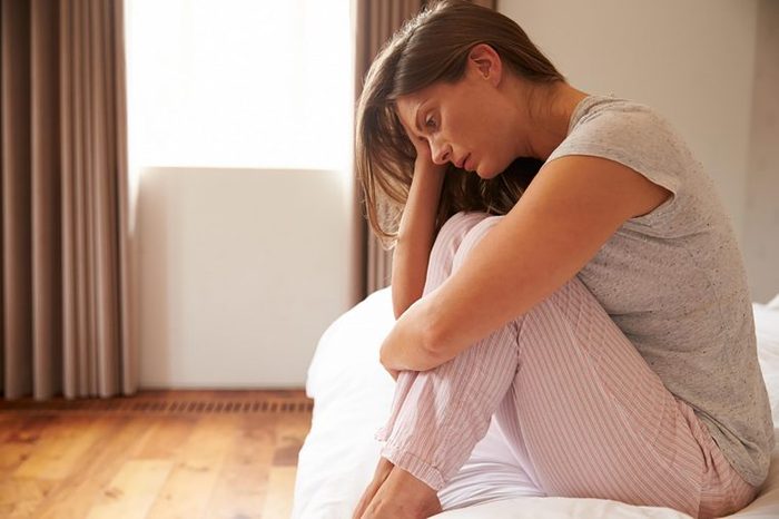 woman looking sad while sitting on bed