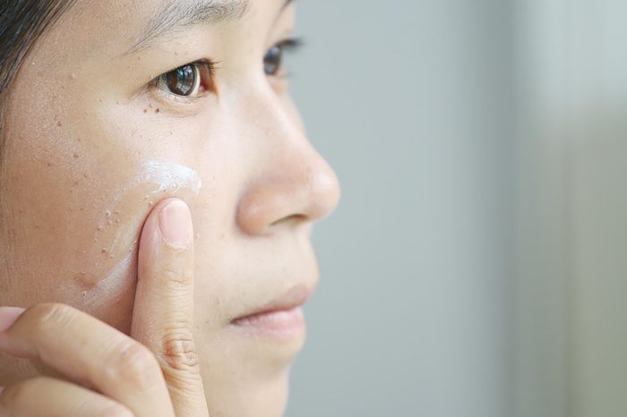 Woman applying foundation to the skin on her cheek.