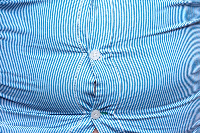 close up of a heavy person's bulging button-up shirt