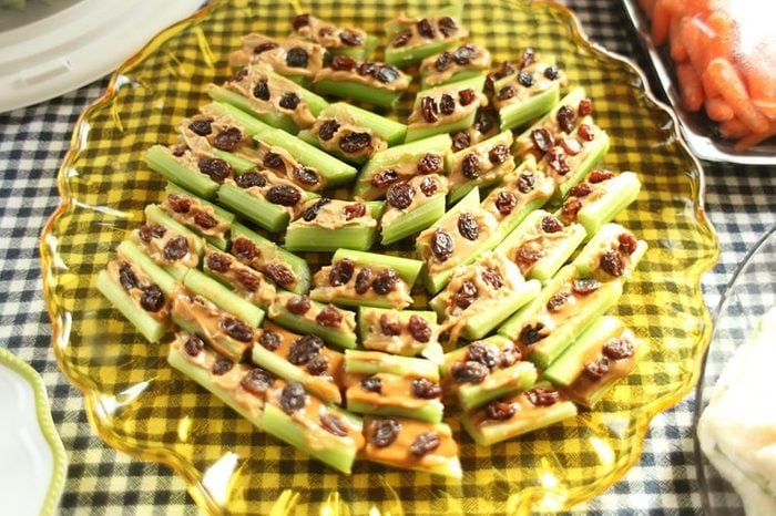 A plate of celery sticks stuffed with peanut butter and topped with raisins, or ants on a log. 