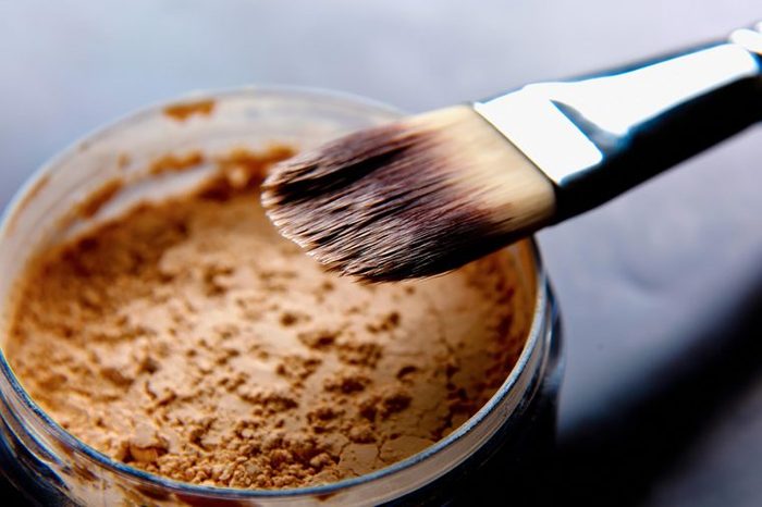 A foundation brush in a jar of makeup powder.