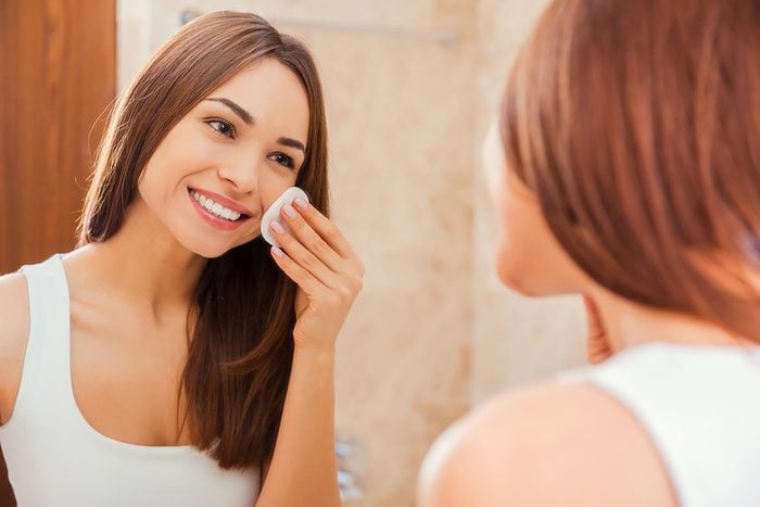 woman looking in mirror and cleaning face