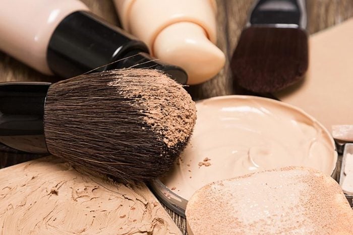 A foundation brush and jars of foundation in shades of beige.