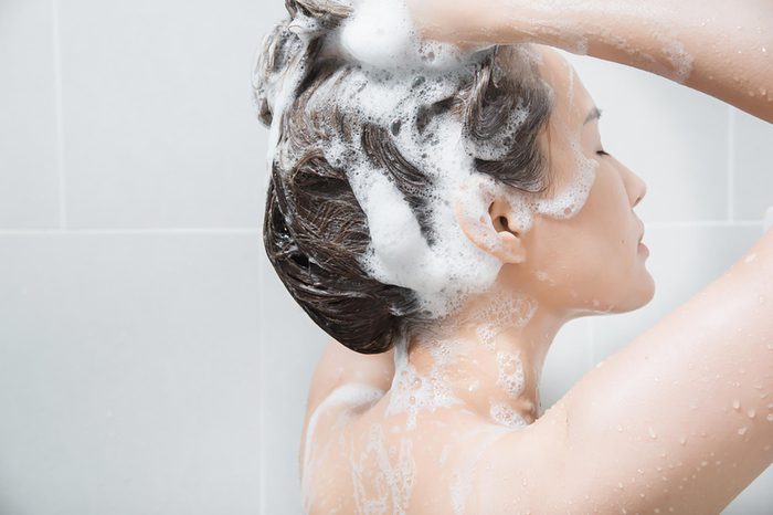 A woman shampooing her hair in the shower.