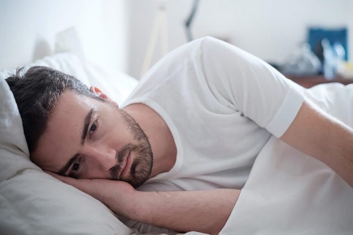 man lying on side in bed, looking sad