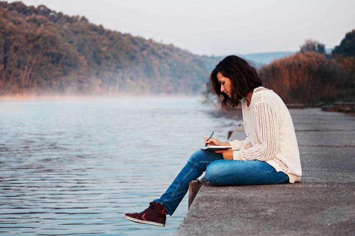 woman sitting on dock writing in journal