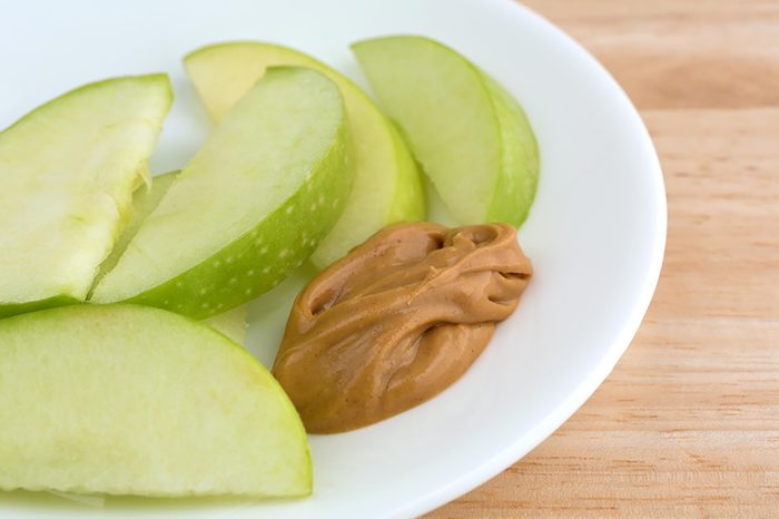 Granny Smith apple slices with a glob of peanut butter on a plate.