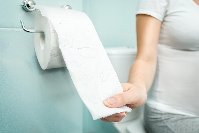 woman on toilet pulling toilet paper