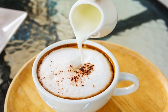 Milk being poured into a cup of cappuccino