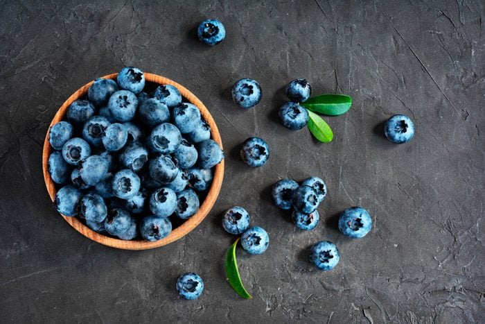 bowl of blueberries and scattered blueberries on a dark background