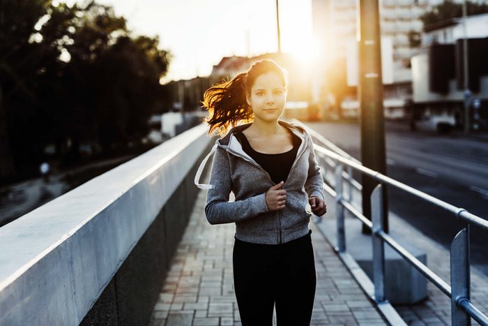 woman jogging outdoors with sun glare