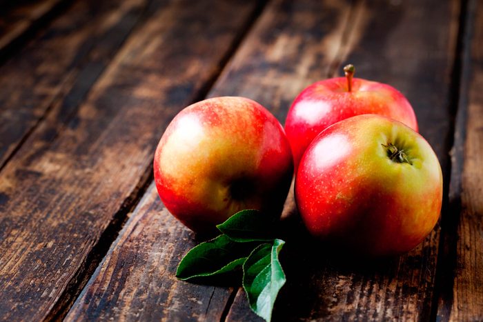rote Äpfel auf verwittertem Holztisch
