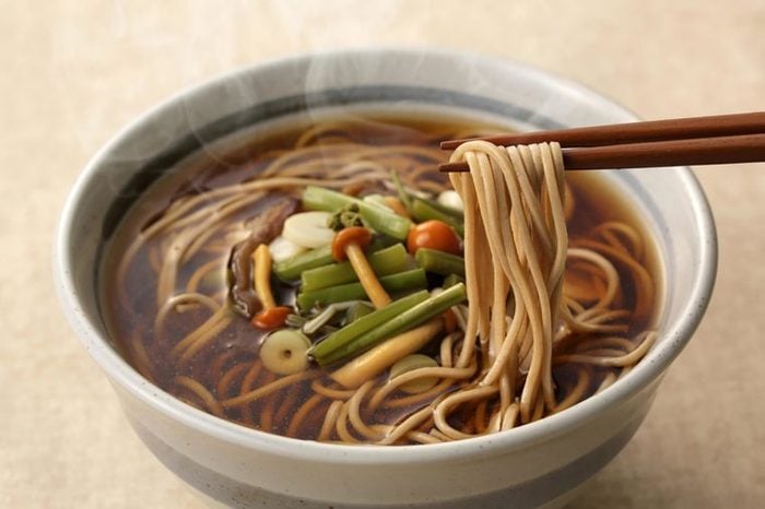 Soba noodles in a gray bowl with chopsticks.