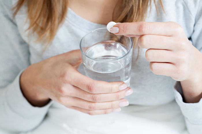 woman holding aspirin and glass of water