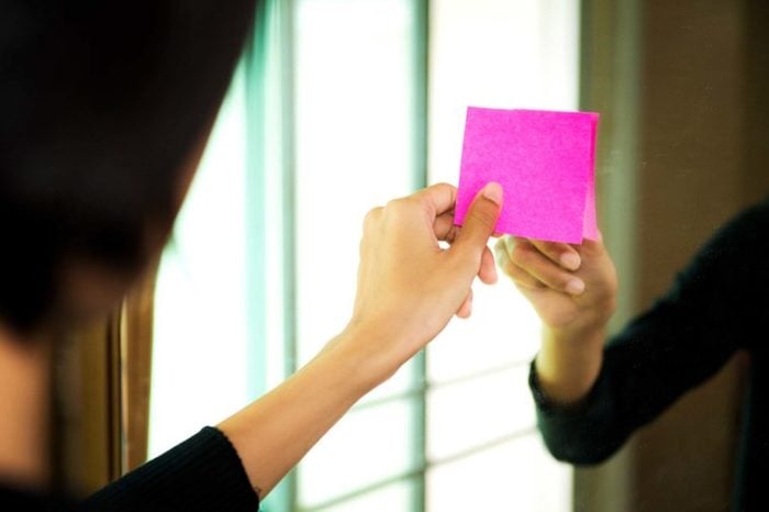 Woman placing pink Post-It on mirror