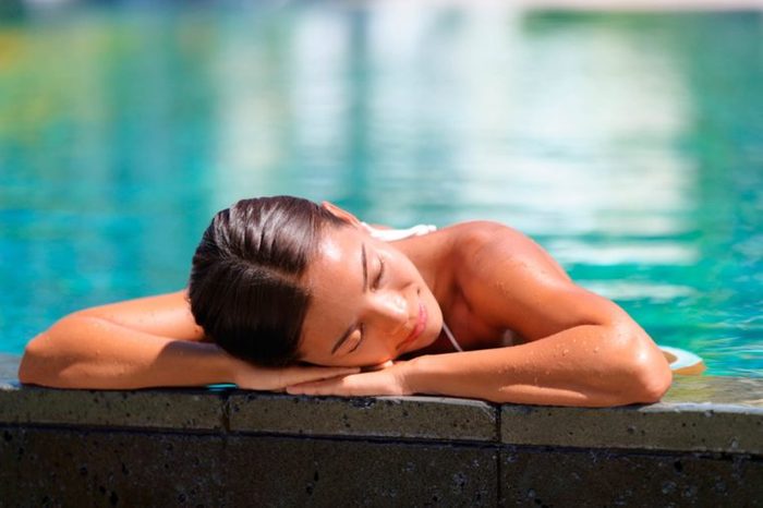 woman in a pool resting her head on the side